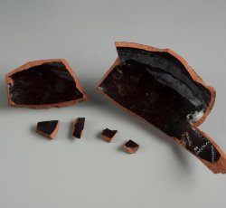 Red-bodied, black lead glazed holloware vessel.