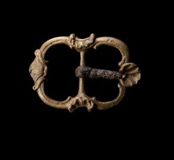 Double framed copper alloy strap buckle with iron tongue and shell decoration.