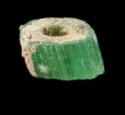 Green, drawn, tubular, simple, tiny bead with thin copper alloy wire embedded.