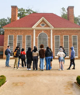 Students standing in front of green house