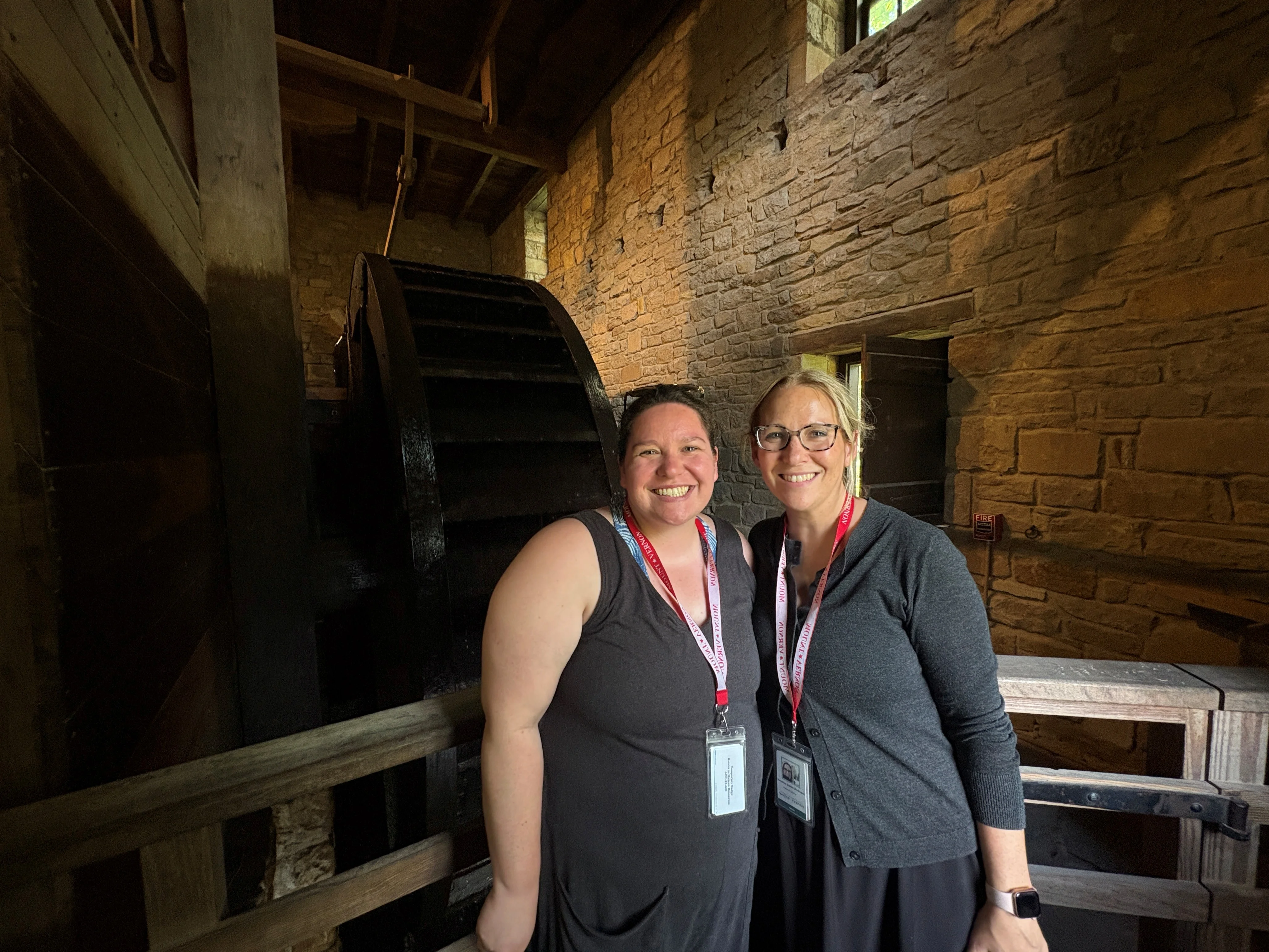 two people standing in front of a large wheel