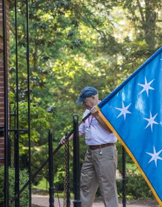 Man raising flag in front of tomb