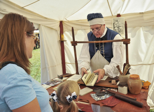 Mother and daughter chat with colonial artisan