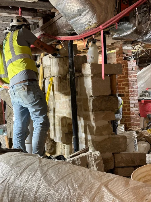 Masons repair a stone wall in the Mansion cellar.