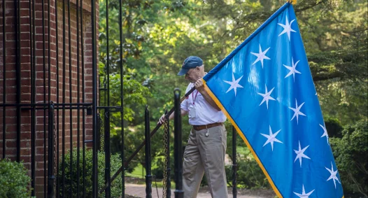 Man raising flag in front of tomb