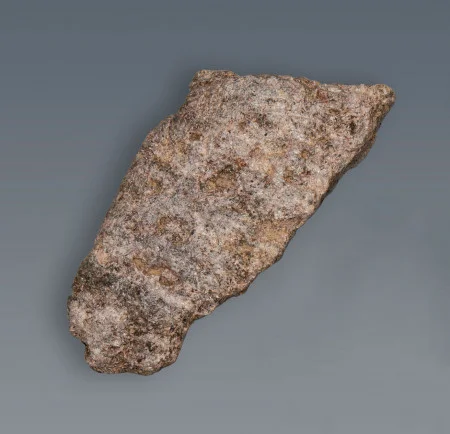 A fragment of the rim of a steatite bowl. Note the quarrying marks, or grooves, on the surface. (MVLA)
