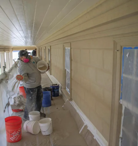 A second coat of sand is cast on the uppermost east front siding. Photo by Caroline Spurry.