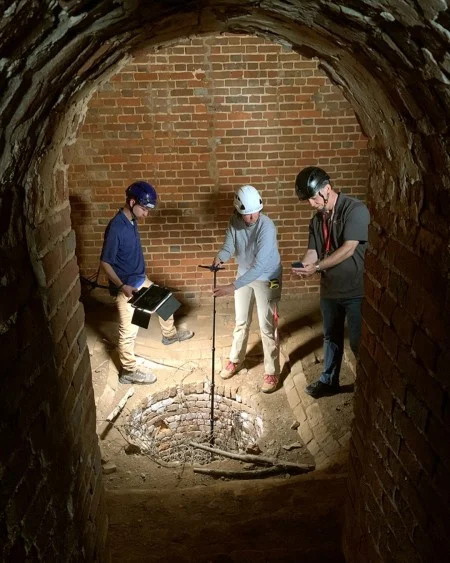 From left to right, Clay Fellows (Preservation Specialist), Riley Morris (Preservation Conservator), and George Brown (Visual Asset Specialist), photograph the sump or drain at the bottom of George Washington’s 18th-century ice house. The well of the ice house extends underground about 18 feet, and the sump at the bottom extends another 7 feet. (MVLA)