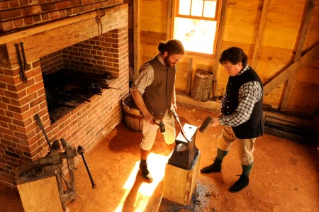 Blacksmith Eric Zieg works with Steve Bashore, director of Historic Trades, to forge a new tool in the reconstructed Blacksmith Shop, which opened in 2009. MVLA. 