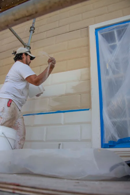 Sand being thrown onto wet paint on the Mansion’s south elevation siding during 2021 restoration work.