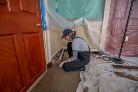Preservation Carpenter Allison Brashears removes a small section of mopboard, which was found to display a handwritten signature and year (1884) on its reverse. (MVLA)