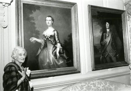Mrs. Cooke stands with original Washington family portraits in the west parlor in 1976. The portraits were on special loan to Mount Vernon from Washington and Lee University. MVLA. 