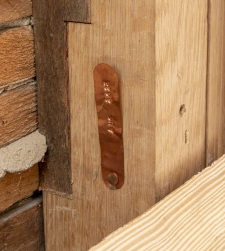 When carpenters need to replace deteriorated wood in the Mansion or outbuildings, the new wood is marked with a copper tag stamped with the year of installation—as demonstrated by this photo from Mount Vernon's wash house. (MVLA) 